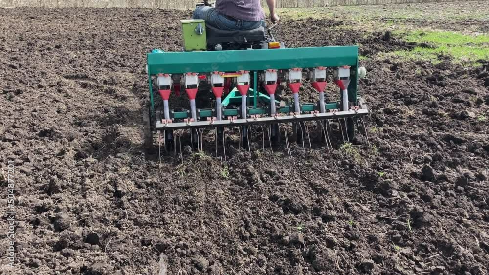 Tractor sowing seeds with seeder driller in field. Process of sowing cereals and other crops. Agricultural field, sowing work in the field. Tractor with seeder performing seeding. High quality 4k foot Tractor sowing seeds with seeder driller in field. Process of sowing cereals and other crops. Agricultural field, sowing work in the field. Tractor with seeder performing seeding. High quality 4k foot