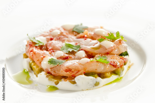 Restaurant dish - shrimp tartare with avocado, cream cheese, sweet chilli sauce on white plate. Ceviche with marinated prawn, avocado and spicy vegetables. Prawn tartare isolated on white background.
