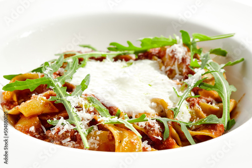 Italian pasta pappardelle with bolognese sauce and parmesan isolated on white background. Pasta tagliatelle with meat ragu and creamy espuma with arugula. Minced beef in tomato sauce with pasta.