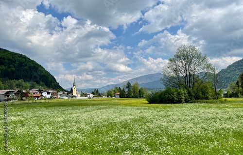 Sommerurlaub in den Bergen in den Alpen mit Kirche und blühender Wiese 