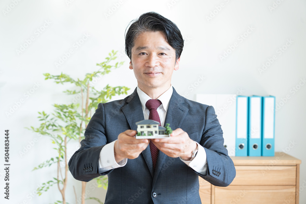 住宅の模型を持つビジネスマン 住宅の模型を持つビジネスマン