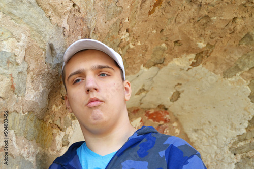 Sad Guy with autism is standing against the wall