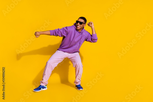 Full length body size view of attractive cheerful cool guy having fun dancing clubbing isolated over bright yellow color background