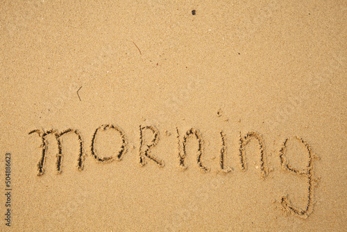 Morning - handwritten on the soft beach sand.
