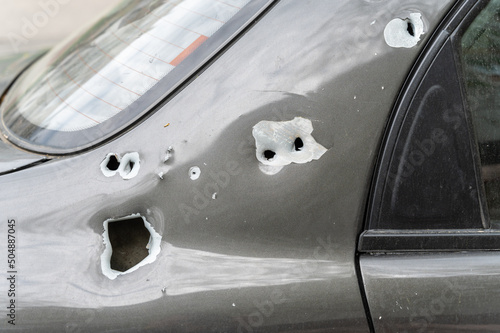 Close-up of the body of the shelled car. A sedan with through holes from shrapnel and bullets. The war in Ukraine 2022. Russian aggression. Shelling of civilians. War crimes concept photo