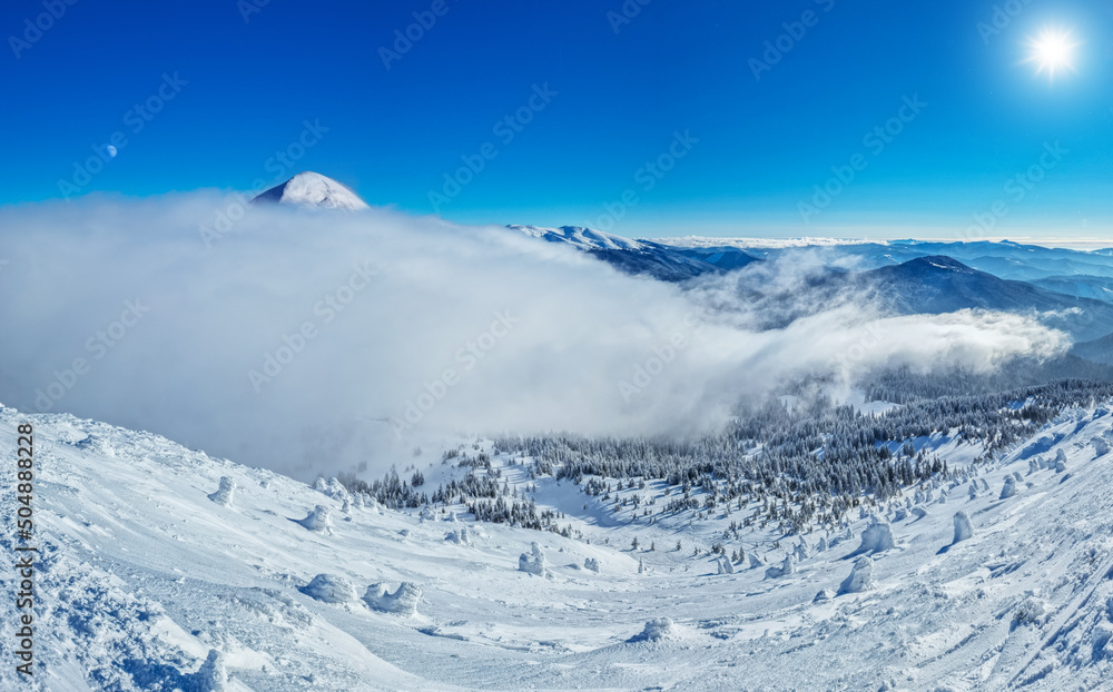 Beautiful sunny winter landscape in thу mountains. Mountain and fir trees covered with snow and clouds.