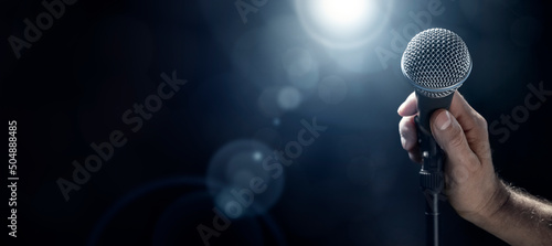 Hand holding microphone with stage lighting background photo