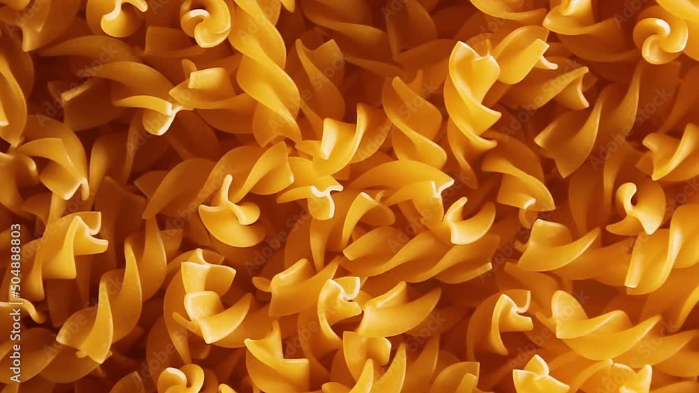 Uncooked Fusilli Pasta - Top View, Close-Up, Low Key Light. Fat and Unhealthy Food. Dry Spiral Macaroni, Rotating Background. Italian Culture and Cuisine. Raw Golden Pasta Pattern. Left Rotation Uncooked Fusilli Pasta - Top View, Close-Up, Low Key Light. Fat and Unhealthy Food. Dry Spiral Macaroni, Rotating Background. Italian Culture and Cuisine. Raw Golden Pasta Pattern. Left Rotation