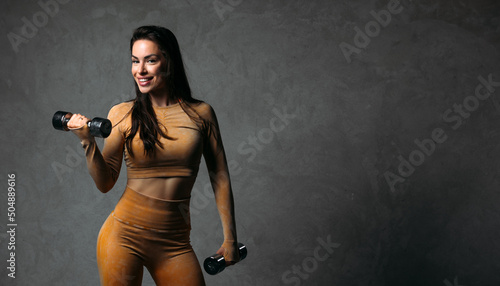 Beautiful fitness girl posing against grey wall, happy skinned fit woman enjoying body positive and vitality