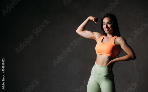 Beautiful fitness girl posing against grey wall background