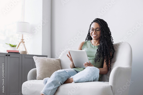 Young smiling woman using digital tablet at home, Leisure, relaxation, online learning, web chat, video call, freelance, modern lifestyle concept photo