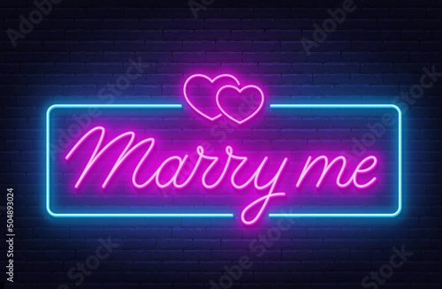 Marry Me neon lettering on brick wall background.