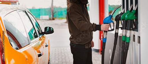 Unrecognizable man refueling car from gas station filling benzine gasoline fuel in car at gas station. Petrol high prices concept photo