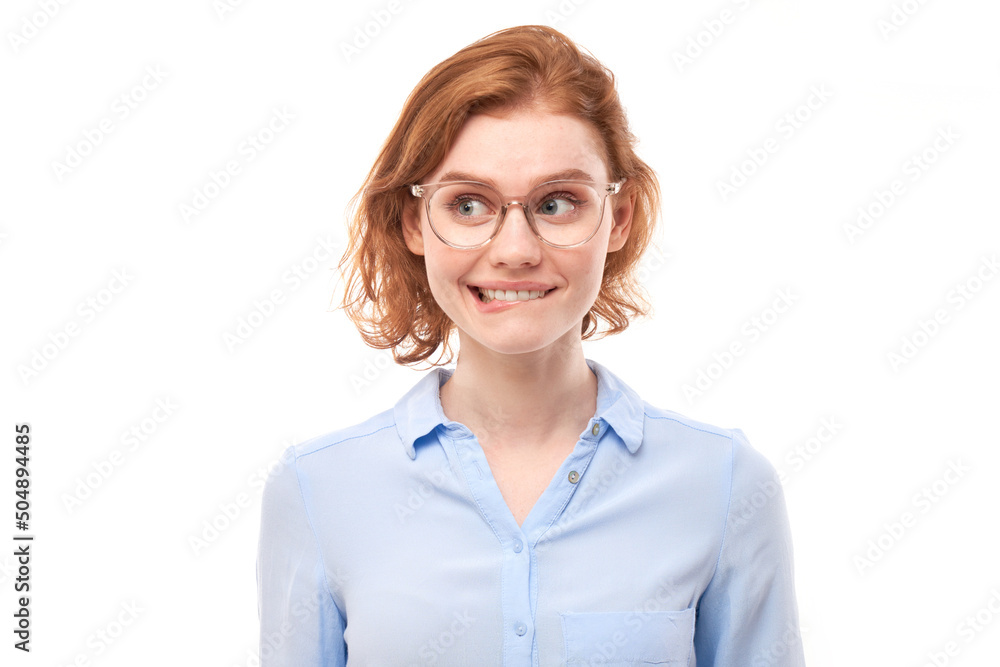 Smart redhead girl in business shirt and glasses grimacing and biting lips thinks doubts, makes decision isolated on white studio background