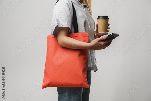 Cropped woman with cotton bag and paper coffee cup, studio shot