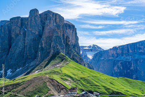 View of Sella Group in the Italian Dolomite Mountain with the hill of green grass and yellow flowers in South Tyrol, Italy.