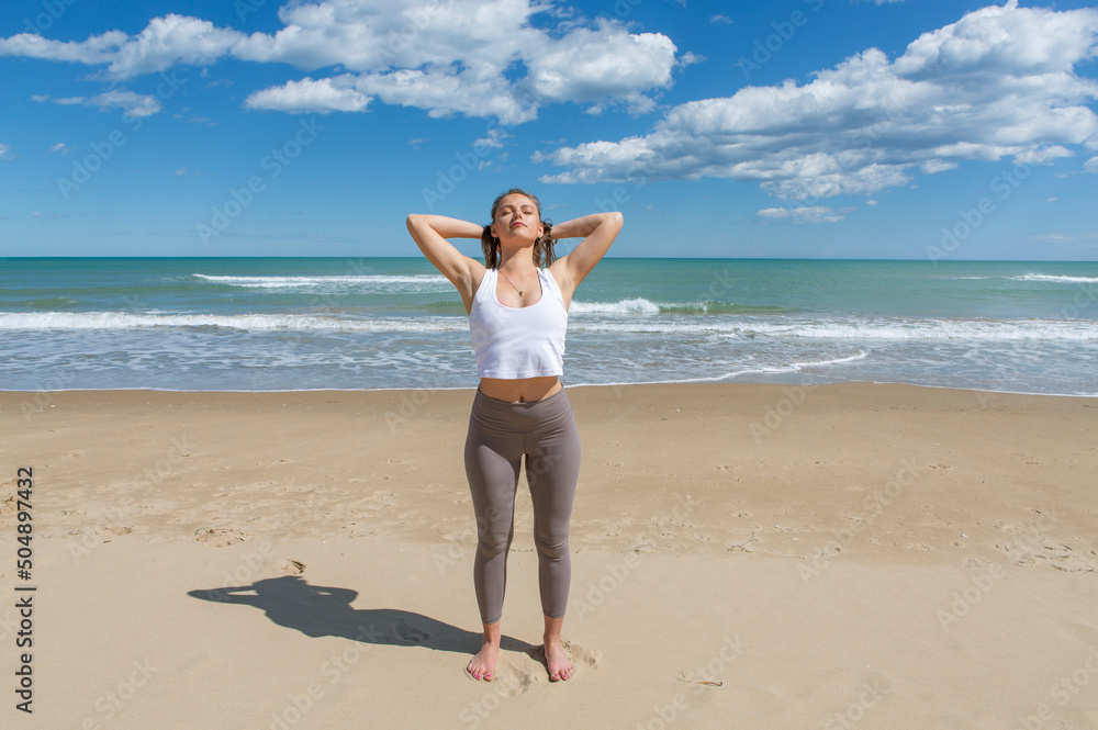 pretty young female athlete stretching on the beach shore pretty young female athlete stretching on the beach shore