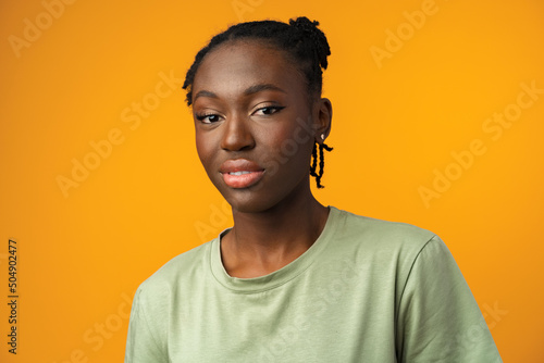 Studio shot of black girl looking suspiciously with skeptical expression in yellow studio photo