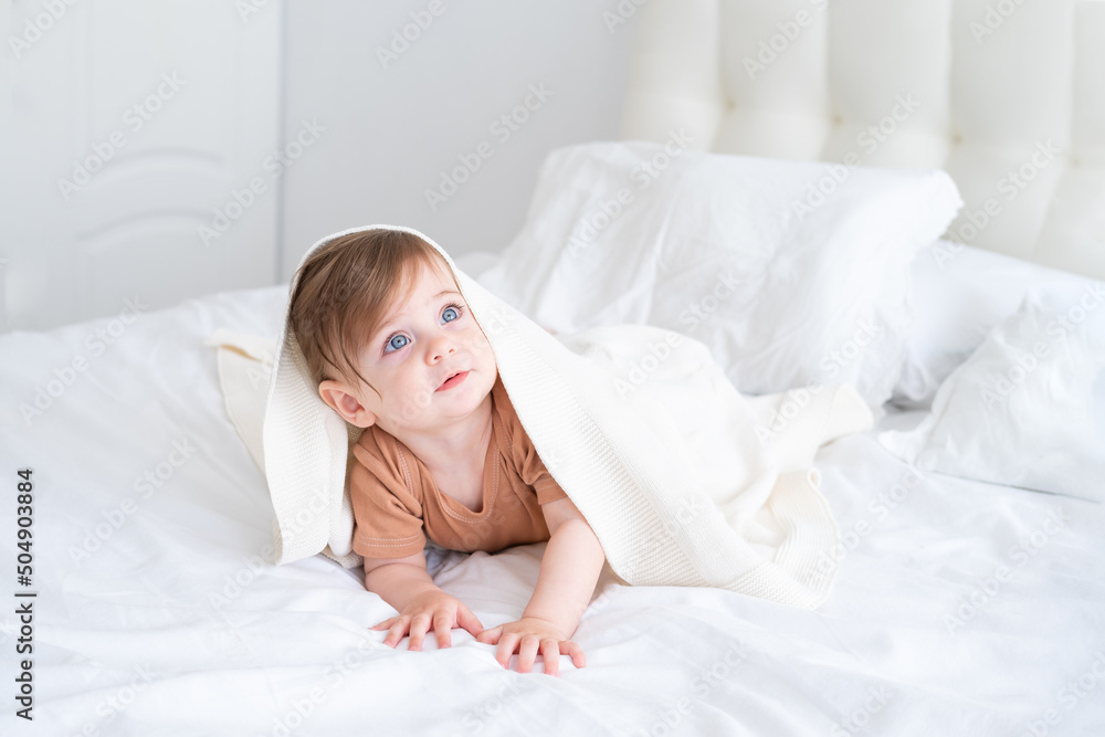 funny baby girl smiling and lying on a white linen under blanket at home funny baby girl smiling and lying on a white linen under blanket at home