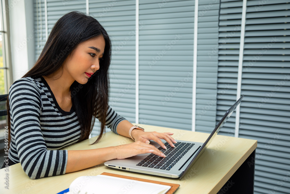 Happy young Asian woman sitting and using laptop in living room by working from home concept Happy young Asian woman sitting and using laptop in living room by working from home concept