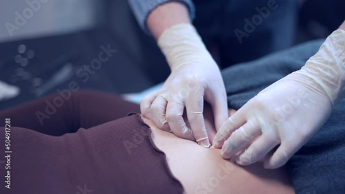 Crop piercer inserting piercing into belly button