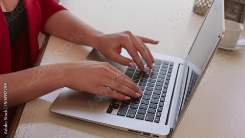 Business woman sitting at her table in office. Red-haired girl manager working in computer. Office worker in red suit in her gorgeous cabinet. 