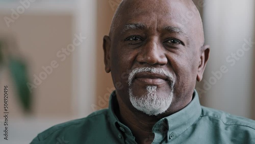 Closeup male portrait indoors senior mature african american grandfather old man biracial 60s boss businessman patient leader in office at home taking off median mask finish end of pandemic recovery photo