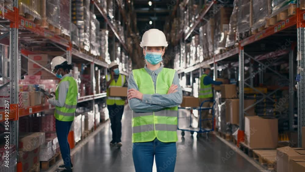 Caucasian pretty female worker standing in hard hat and face mask in warehouse between many shelves with boxes and goods looking at camera. Delivery business, worker, close up Man talking on cellphone Caucasian pretty female worker standing in hard hat and face mask in warehouse between many shelves with boxes and goods looking at camera. Delivery business, worker, close up Man talking on cellphone