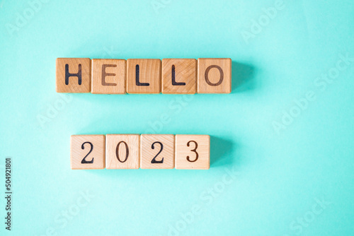 2023 word is made of wooden blocks on the turquoise background. Happy New Year