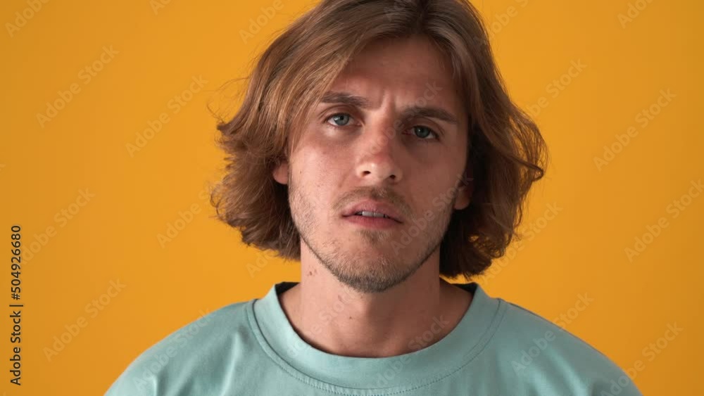 Upset blond man saying no at the camera in the yellow studio Upset blond man saying no at the camera in the yellow studio