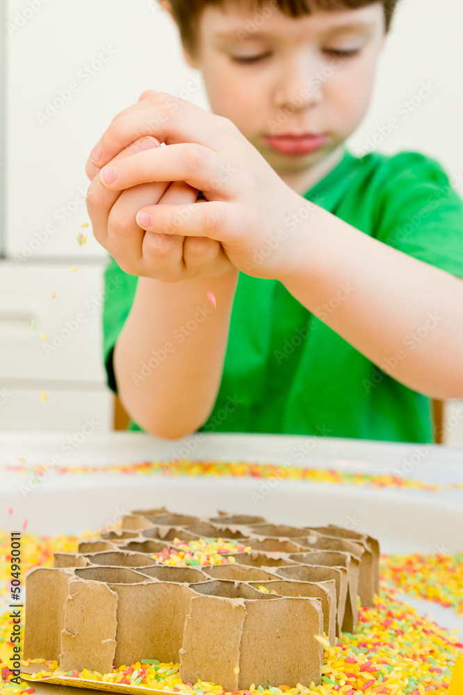 Boy is playing with artificial flowers, bees and a paper
