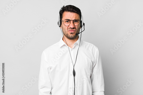 young adult hispanic man feeling sad and whiney with an unhappy look and crying. telemarketer concept photo