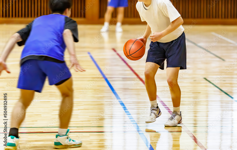 体育館でバスケットボールをする学生