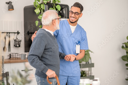 Nurse assisting a patient to walk with a walking stick