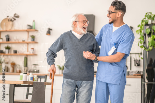Patient leaning on the cane supported by a young nurse