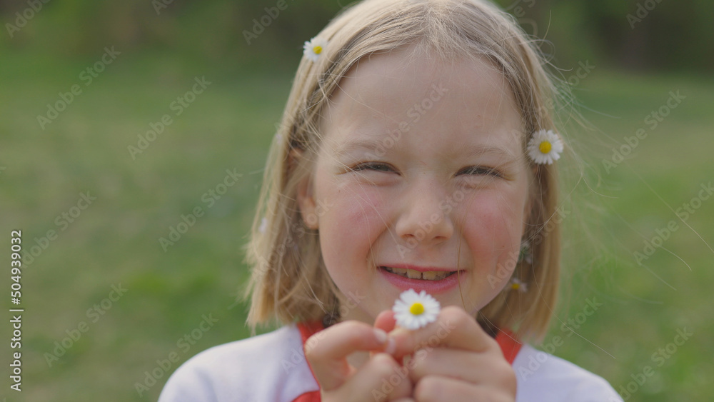 Blonde girl on a background of nature smiles at the camera with chamomile flowers in her hair and hands. The concept of health, beauty and naturalness Blonde girl on a background of nature smiles at the camera with chamomile flowers in her hair and hands. The concept of health, beauty and naturalness