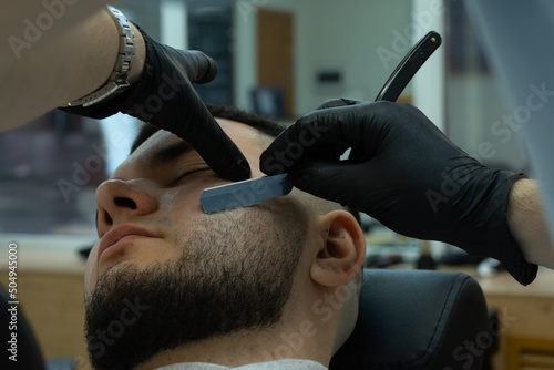 Fotografía barber shaves the client with cut throat razor