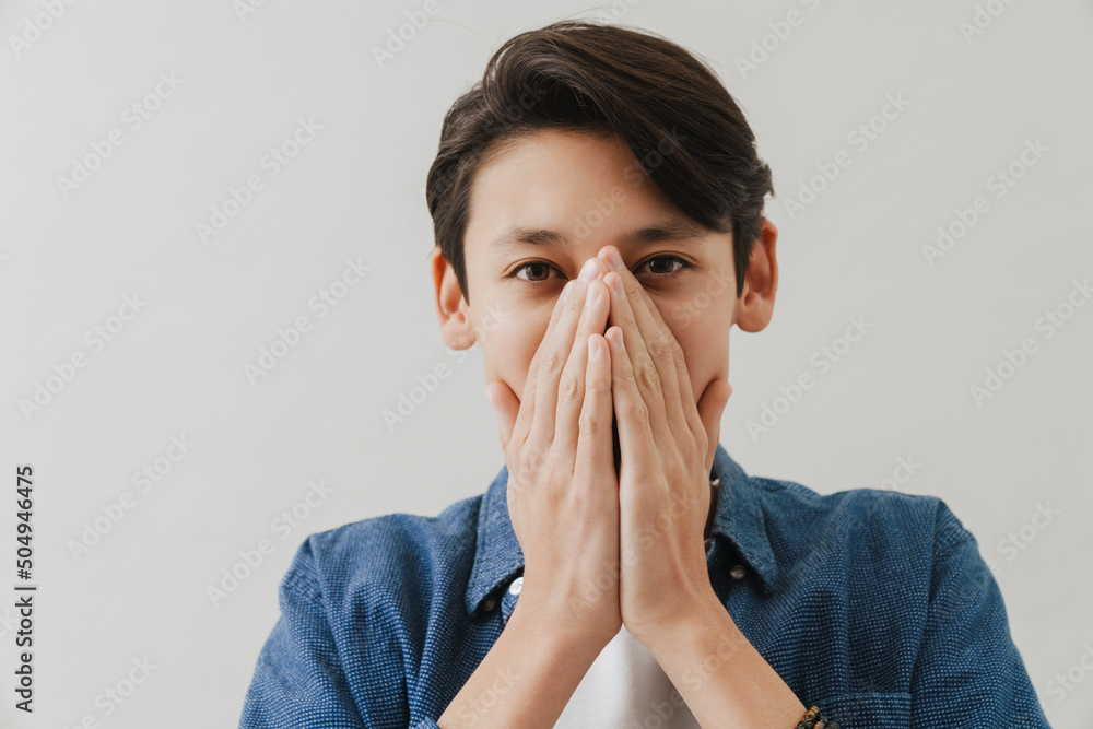 Asian boy wearing shirt covering his mouth while posing on camera Asian boy wearing shirt covering his mouth while posing on camera