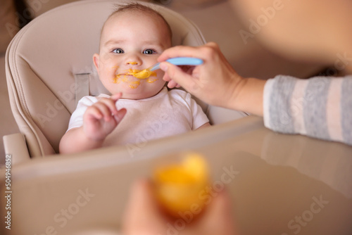 Cheerful baby eating in high chair