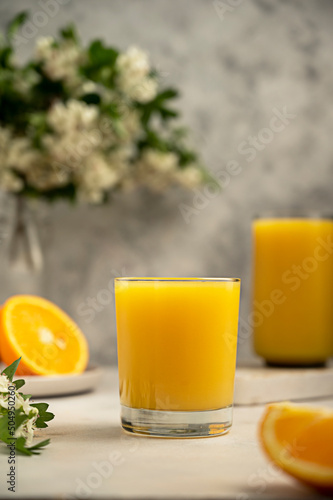 Two glass of orange juice with fresh orange fruit. Summer refreshing drink. Blooming tree brunch