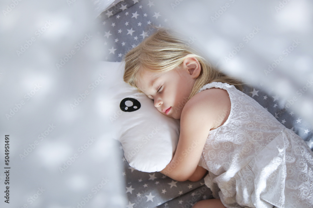 Cute toddler girl sleeping in bed sheets with stars pattern and cloud shaped pillow Cute toddler girl sleeping in bed sheets with stars pattern and cloud shaped pillow