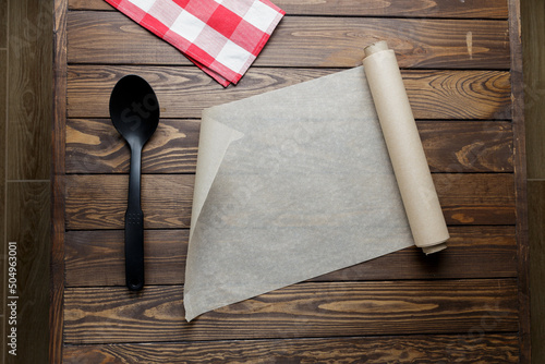 baking paper and spoon on the table. baking paper on a wooden background. unrolls a roll of baking paper. photo