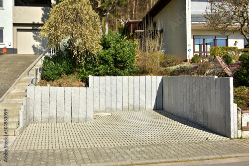 Geneigtes Wohngrundstück an Wohnhausneubau, neu terrassiert mit Natursteinmauer und initialer Hinterpflanzung mit Ziergras, Gartenpflanzen, Zierpflanzen photo