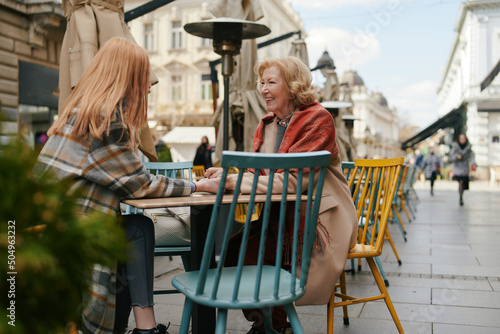 A grandmother bonding with her granddaughter while sitting in cafe and holding hands.