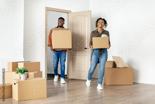 African American Spouses Entering Their New Apartment Holding Moving Boxes © Prostock-studio