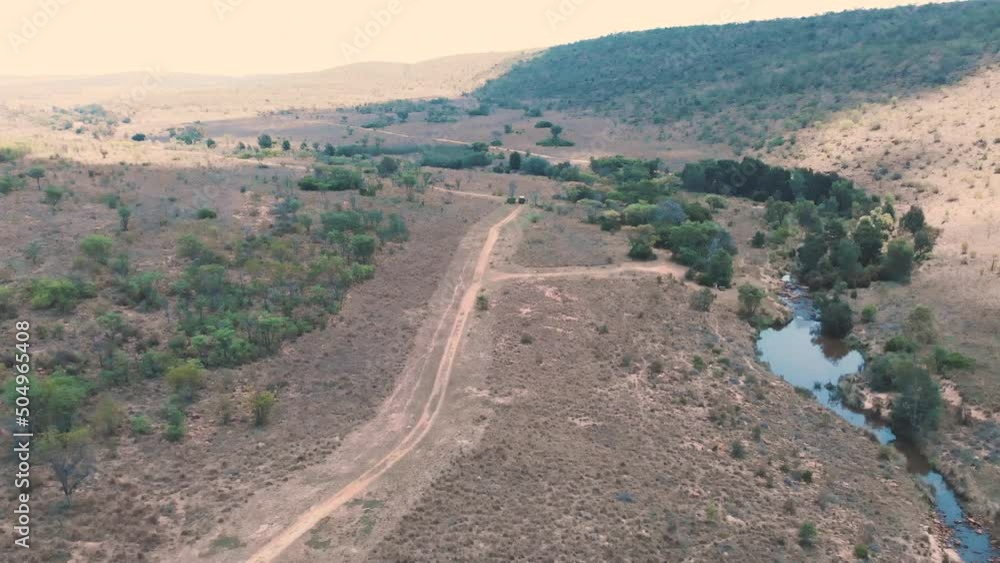 Long drone shot of safari jeep on dirt road in african savannah. Long drone shot of safari jeep on dirt road in african savannah.