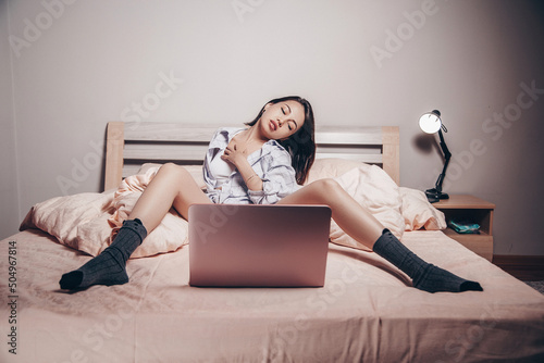a young Asian webcam model girl is sitting in front of a laptop with her legs spread. she communicates and shows her charms. low depth of focus,artistic photo processing