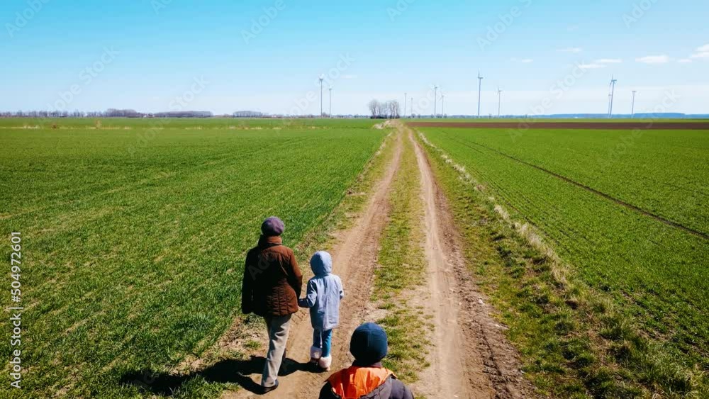 Sad family of ukrainian refugees with children and suitcase walking away from russian invasion by road between fields. Concept of peaceful and carefree life without armed conflicts Sad family of ukrainian refugees with children and suitcase walking away from russian invasion by road between fields. Concept of peaceful and carefree life without armed conflicts