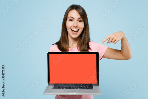 Young happy caucasian woman 20s in pink t-shirt hold use work point index finger on laptop pc computer with blank screen workspace area isolated on pastel plain light blue background studio portrait © ViDi Studio