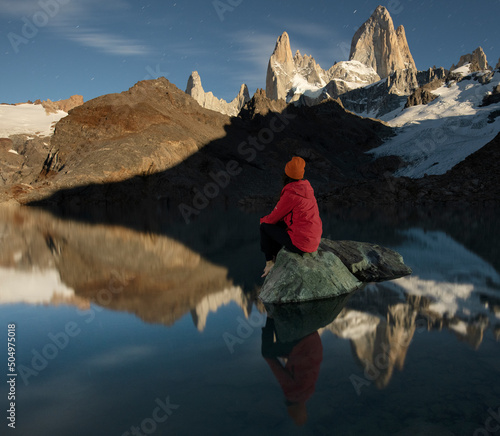 A hiker sits on a rock in Laguna de los Tres in front of the ico photo